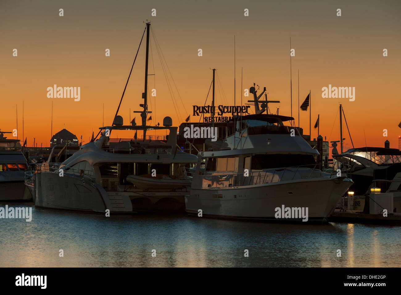 Le ciel est orange lever du soleil derrière les bateaux de plaisance amarrés dans l'une des marinas de l'Inner Harbor de Baltimore, Maryland. Banque D'Images