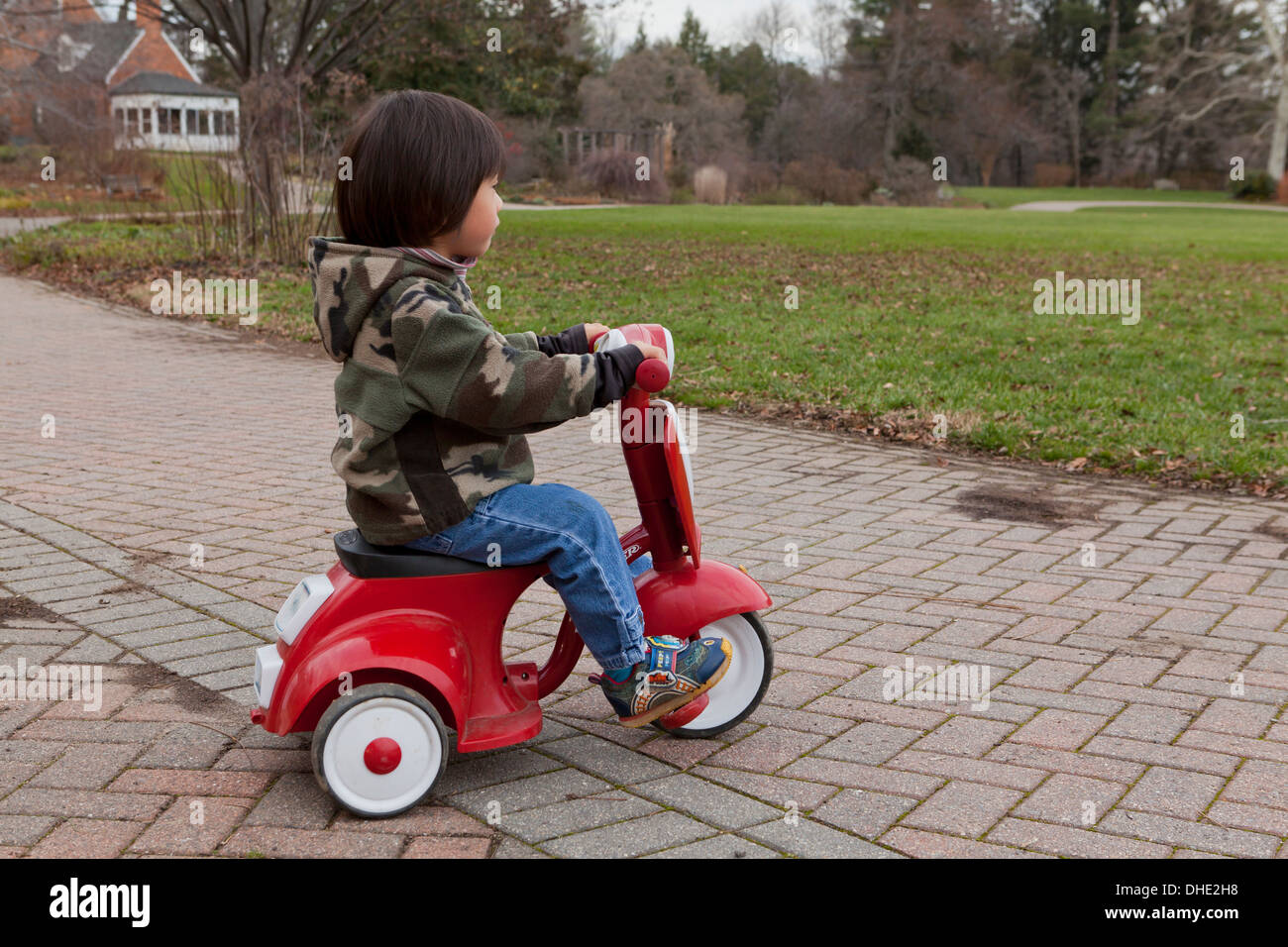 Asian child riding tricycle Radio Flyer Banque D'Images