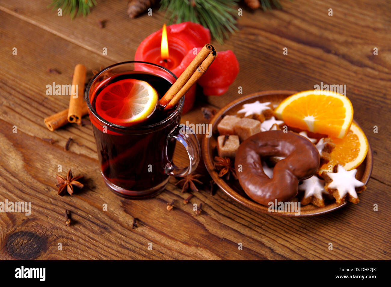 Vin chaud dans du verre, avec le bâton de cannelle, des bougies et des bonbons, soft focus Banque D'Images