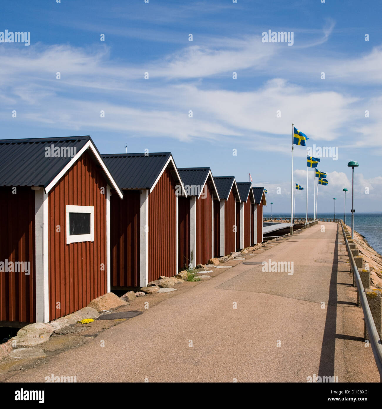 Une rangée de hangars à bateaux sous une rangée de drapeaux suédois à la marina à Båstad, la Suède. Banque D'Images