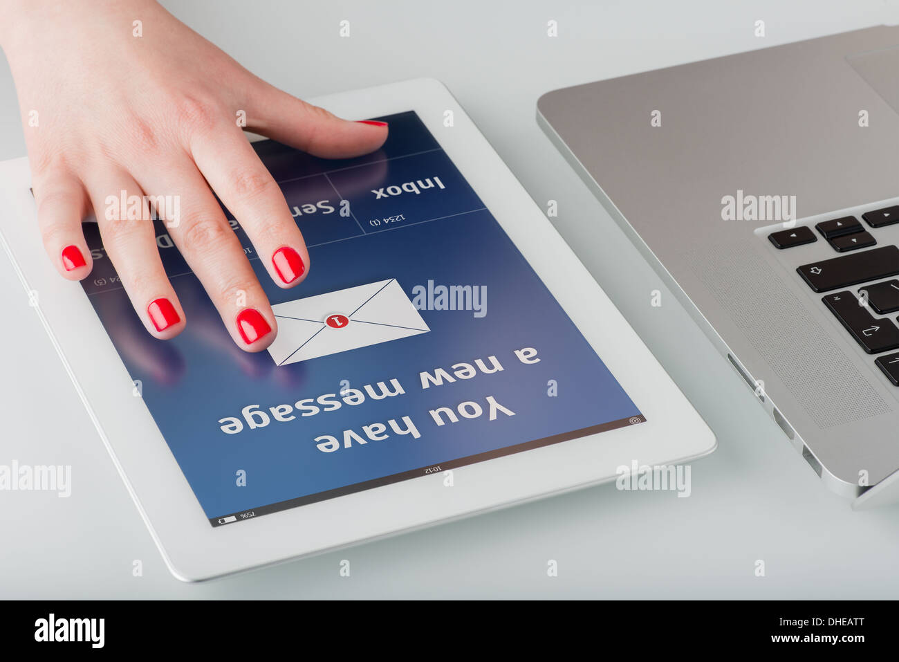 Woman's hand avec manucure rouge ouvre un nouvel e-mail sur un ordinateur tablette. Banque D'Images