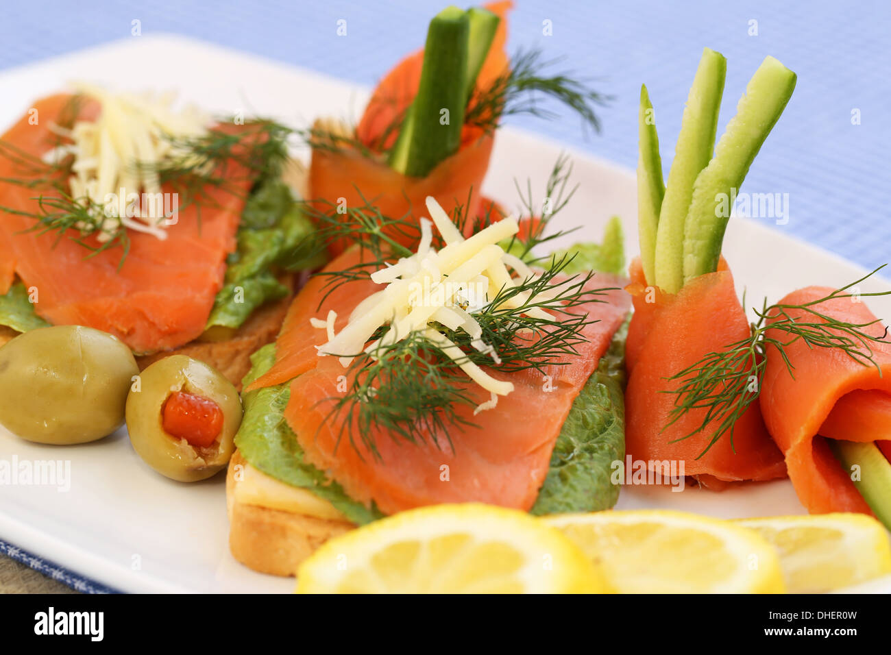 Sandwiches au saumon, fromage, laitue, les herbes sur la plaque, les olives et les citrons. Banque D'Images