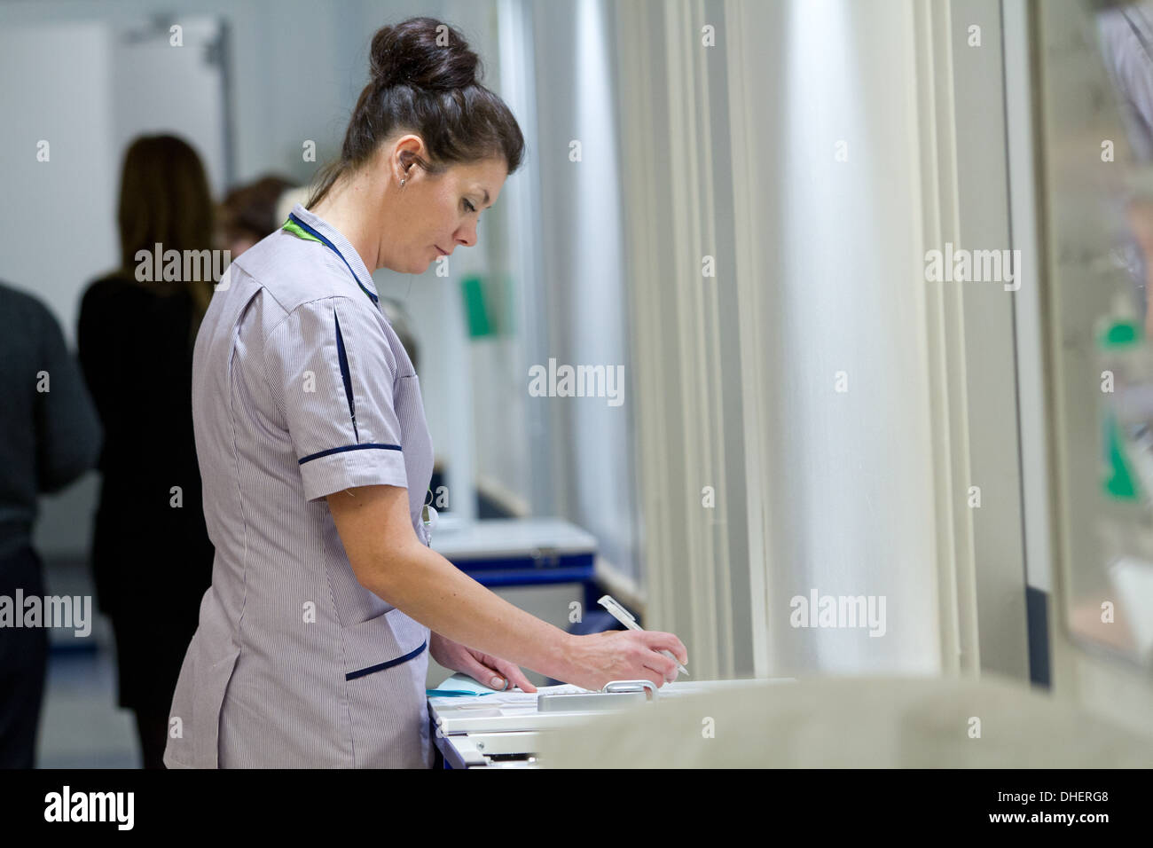 Une infirmière remplit quelques formalités administratives à une réception du NHS UK Banque D'Images