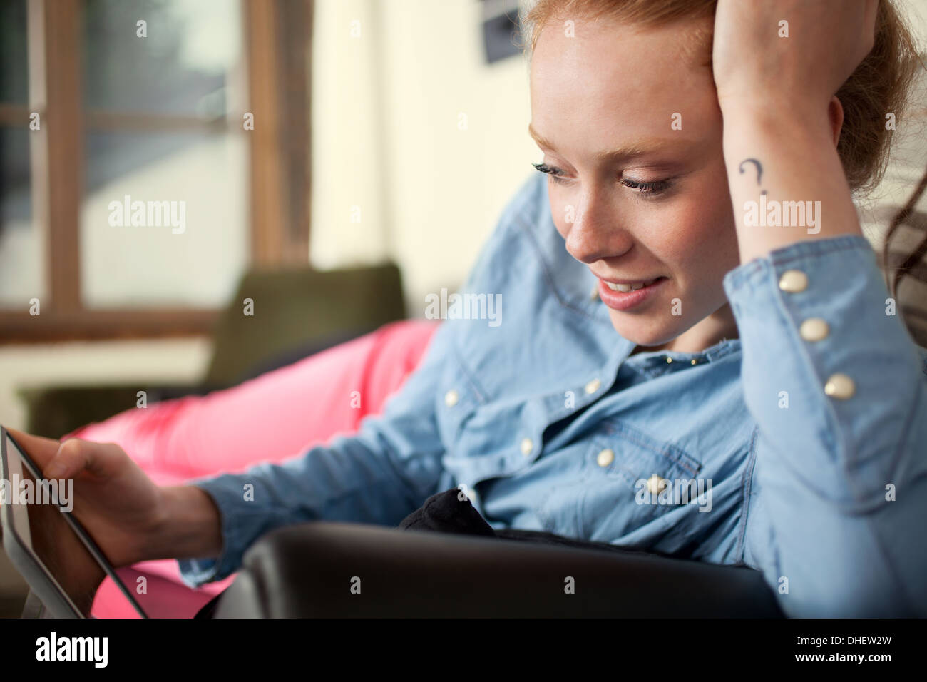 Jeune femme avec un point d'interrogation tattoo using digital tablet Banque D'Images