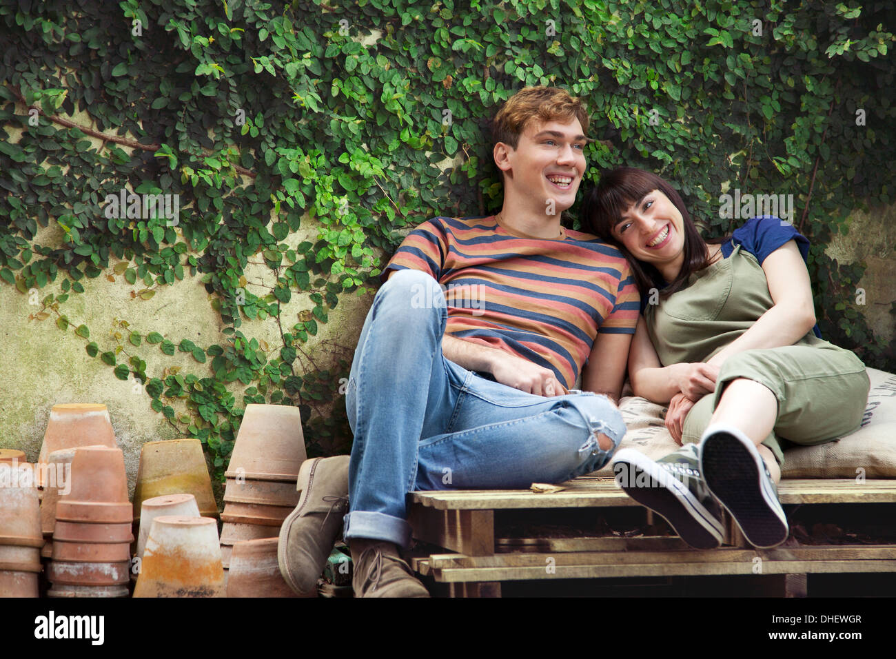 Couple assis sur des palettes de bois, avec cache-pots Banque D'Images