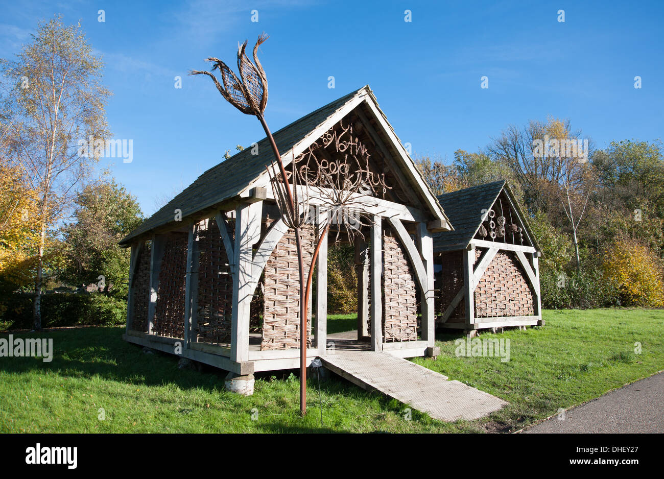 Femme regardant les huttes éducatives Native Seed Hub à Wakehurst dans le West Sussex qui fait partie des jardins botaniques de Kew Banque D'Images