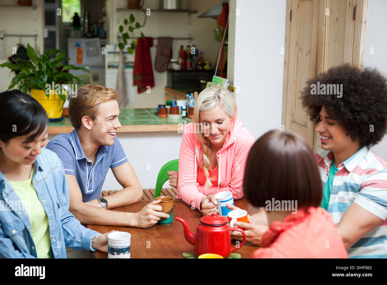 Groupe de jeunes amis discutant autour d'une table de cuisine Banque D'Images