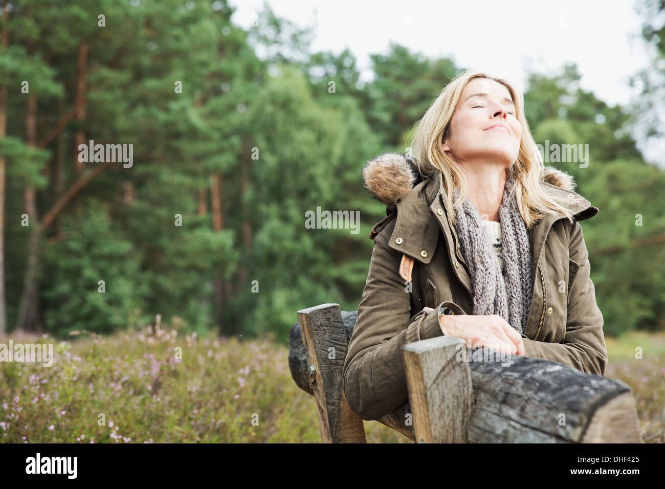 Mid adult woman sur banc avec les yeux fermés Banque D'Images