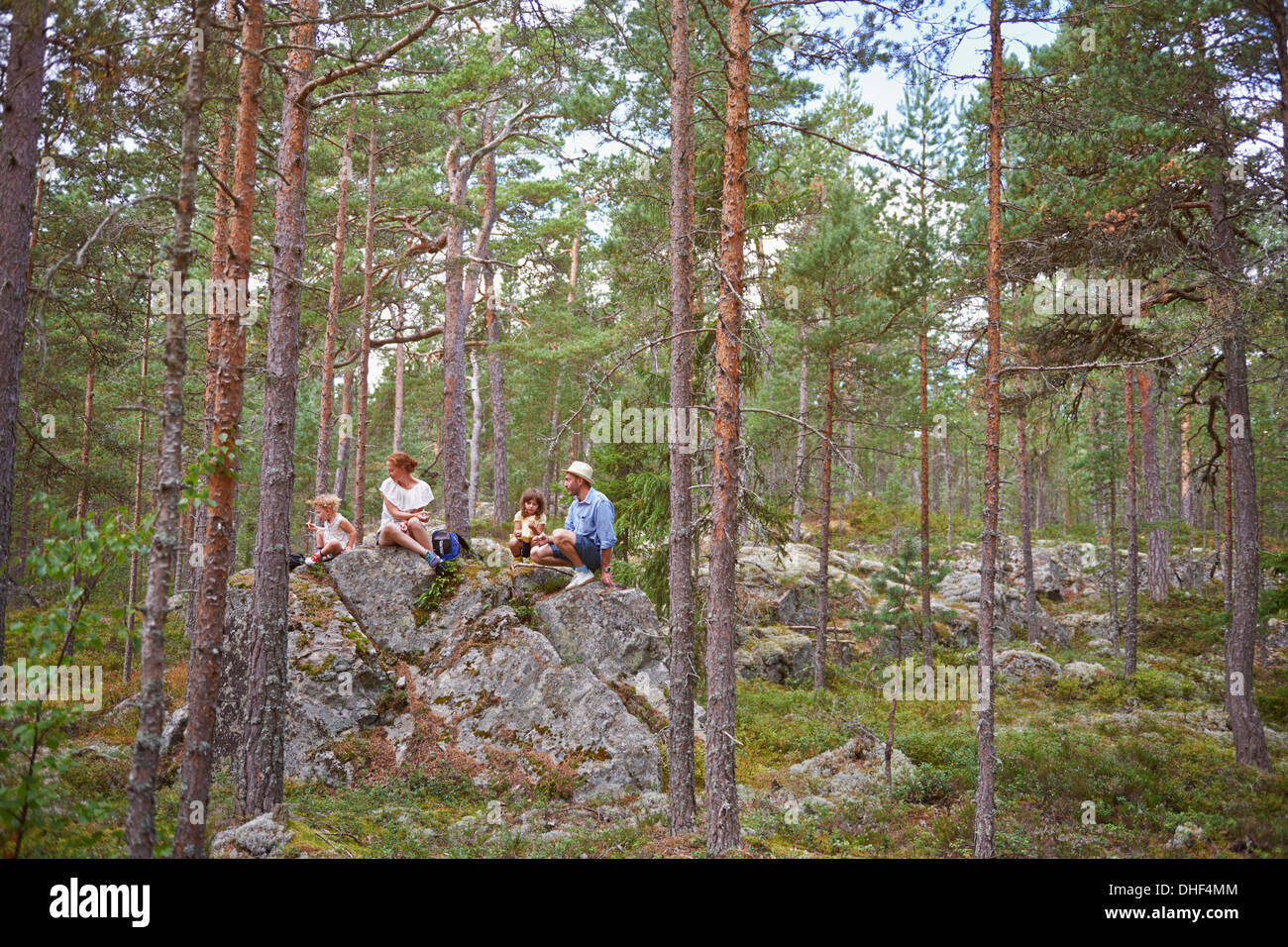 Family sitting on rocks in forest eating picnic Banque D'Images