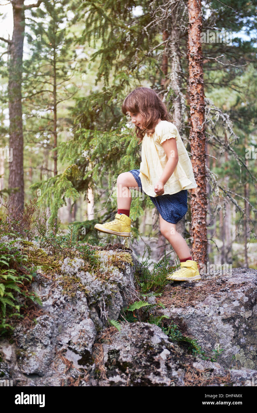 Girl climbing sur les rochers en forêt Banque D'Images