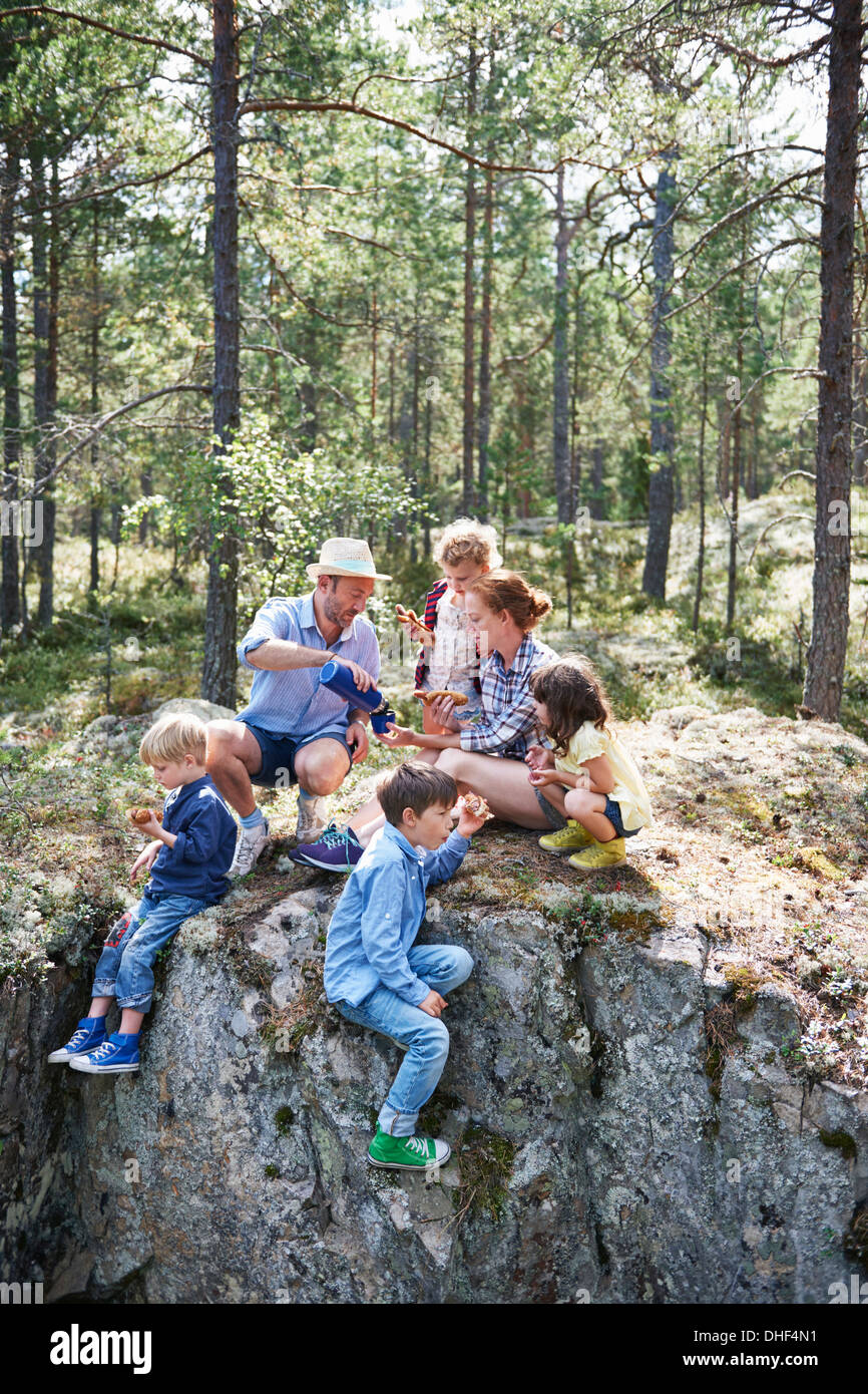 Family sitting on rocks in forest eating picnic Banque D'Images