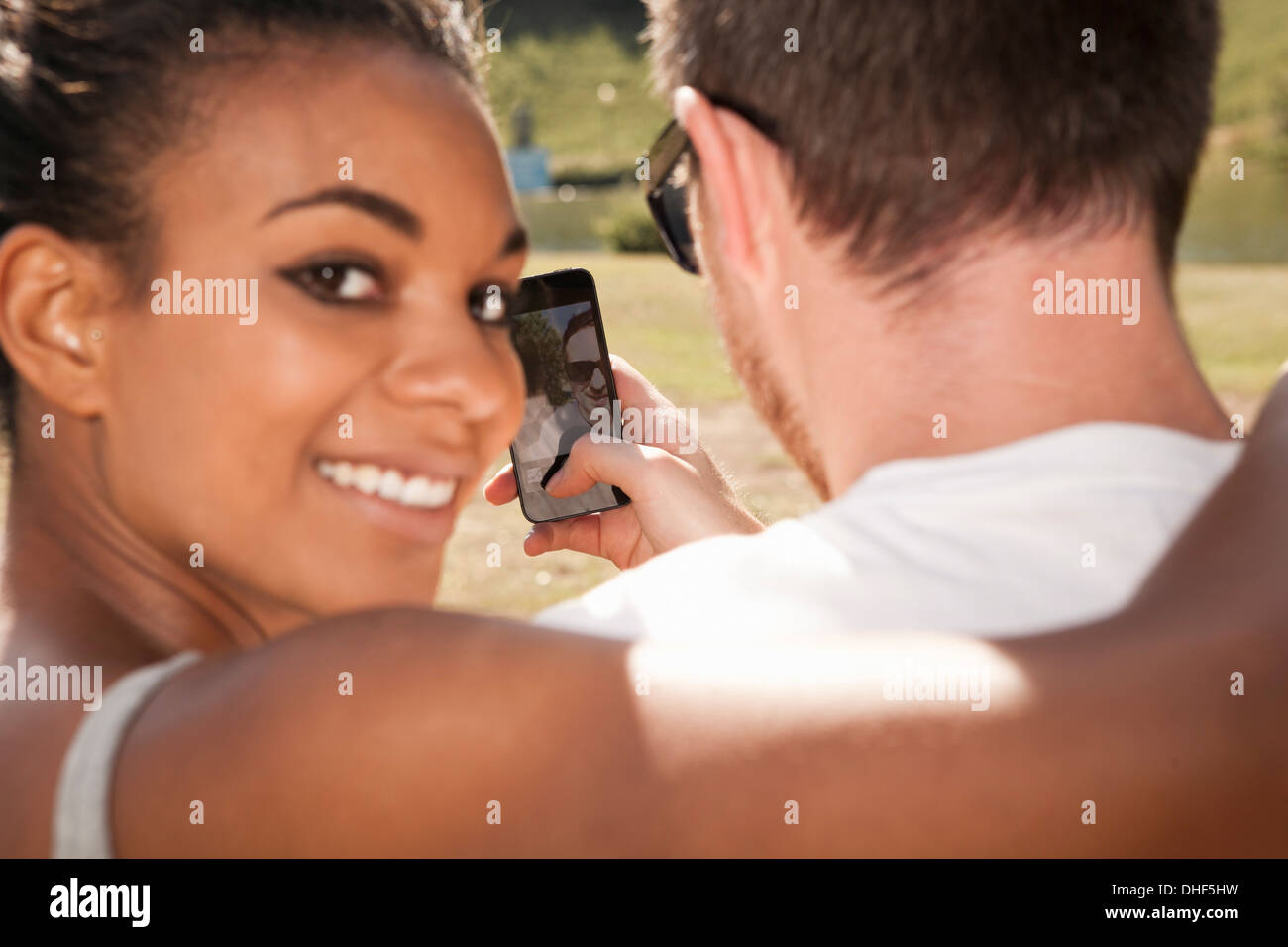 Couple photo d'eux-mêmes avec téléphone, woman looking over shoulder Banque D'Images