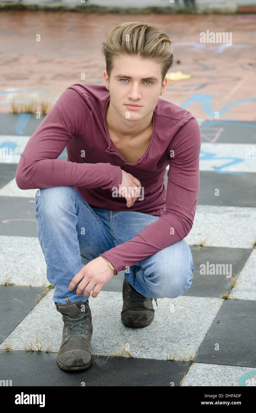 Beau jeune homme blond, yeux bleus, assis sur le plancher à carreaux à  l'extérieur Photo Stock - Alamy