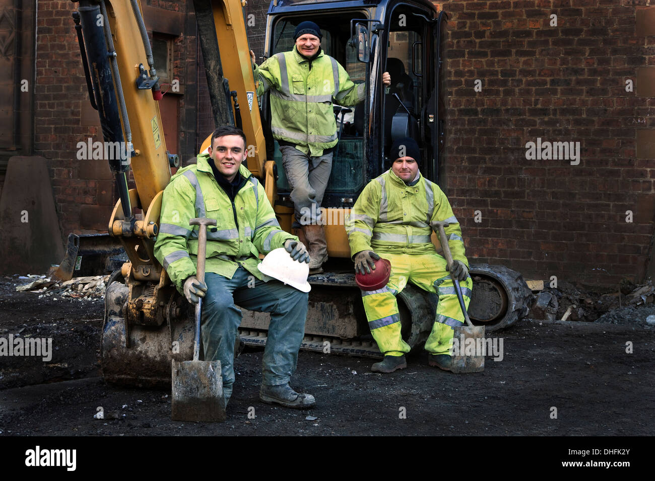 Trois ouvriers sur place posant sur leurs JCB digger Banque D'Images