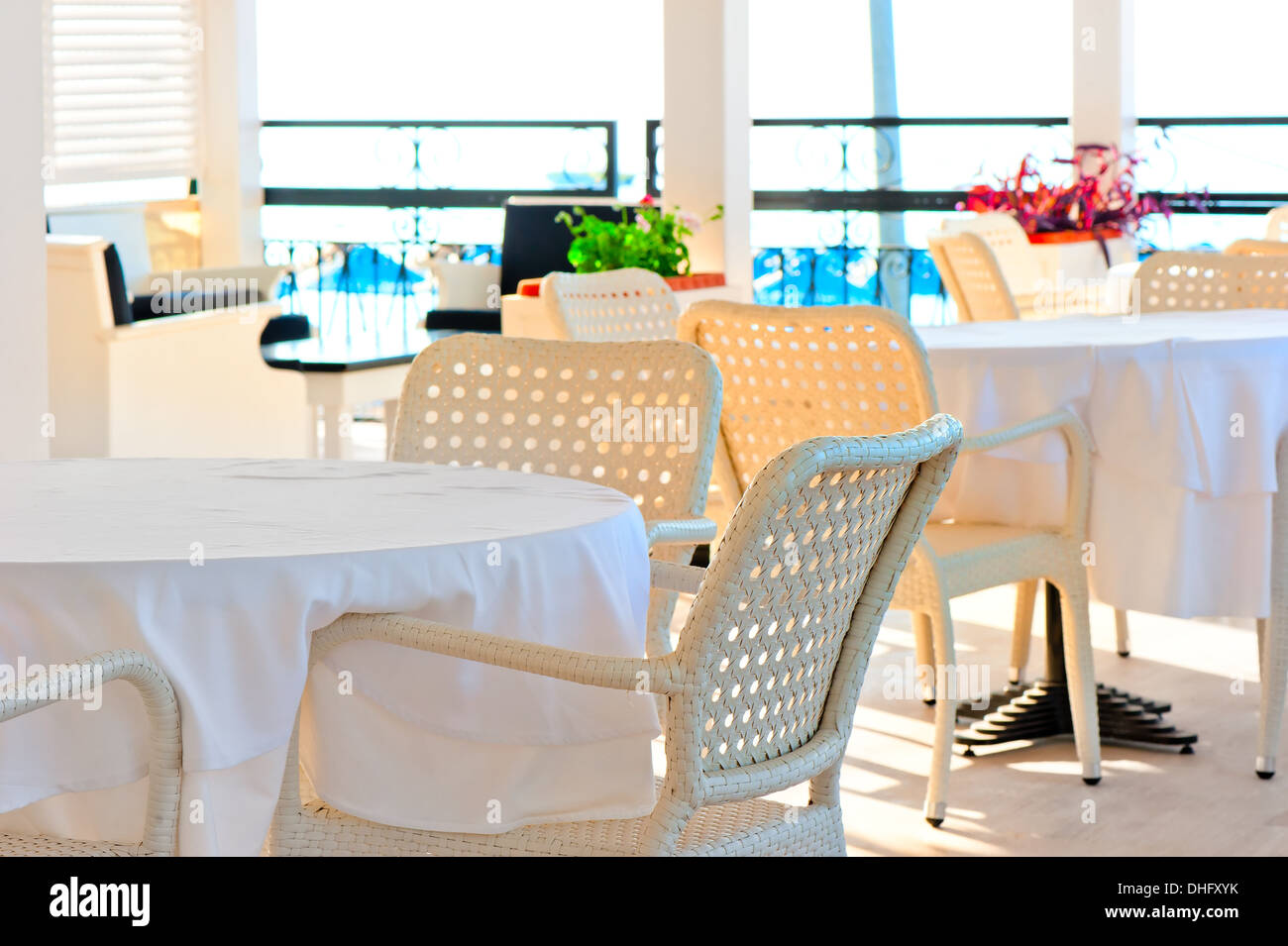 Couverts de table avec une nappe blanche et des chaises en osier Banque D'Images