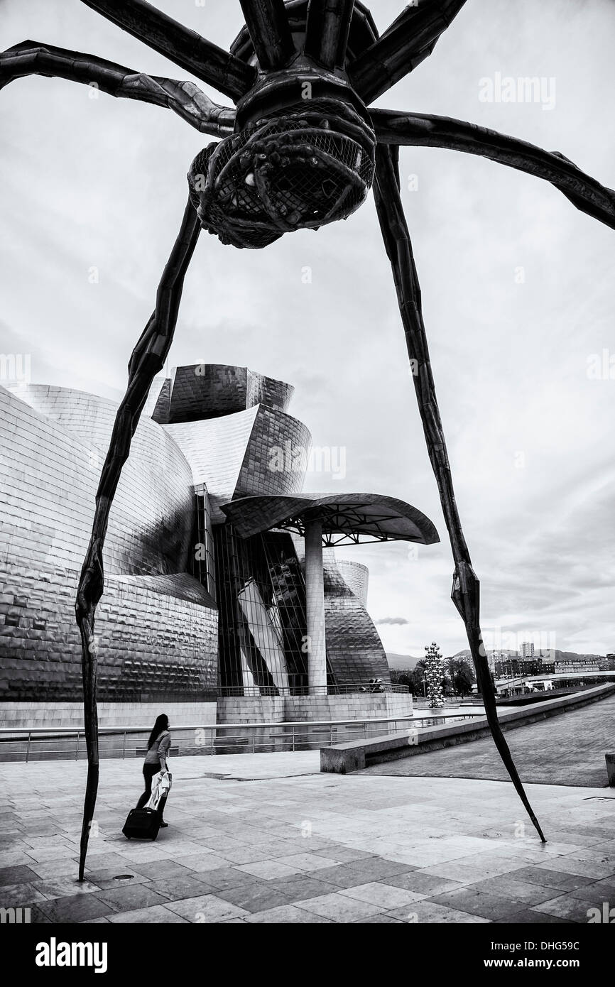 Une femme marche sous la grande araignée-comme sculpture maman de Louise Bourgeois à côté du Musée Guggenheim à Bilbao, en Espagne. Banque D'Images