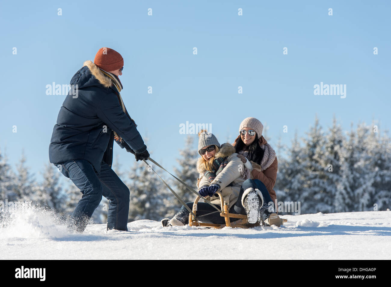 Jeune homme tirant sur la neige Traîneau filles hiver campagne Banque D'Images