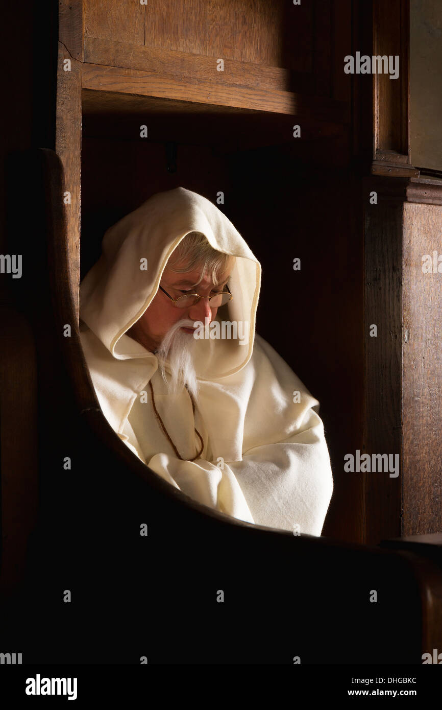 Un moine assis à capuchon dans une chorale d'une église médiévale du siège Banque D'Images