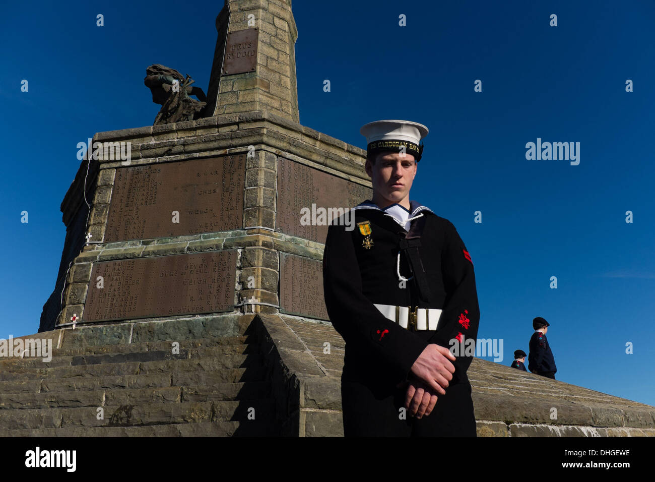 Pays de Galles Aberystwyth UK, dimanche 10 novembre 2013 un cadet de la famille se tient sous le monument aux morts à Aberystwyth, sur Dimanche du souvenir 2013. Des centaines de personnes se sont rassemblées sur la pointe au château d'Aberystwyth pour assister à la cérémonie annuelle. Des représentants des forces armées et de nombreux groupes locaux mis à pavot rouge des couronnes à la base du monument commémoratif de guerre emblématique de la ville qui fait face à la mer. Crédit Photo © Keith morris : Keith morris/Alamy Live News Banque D'Images