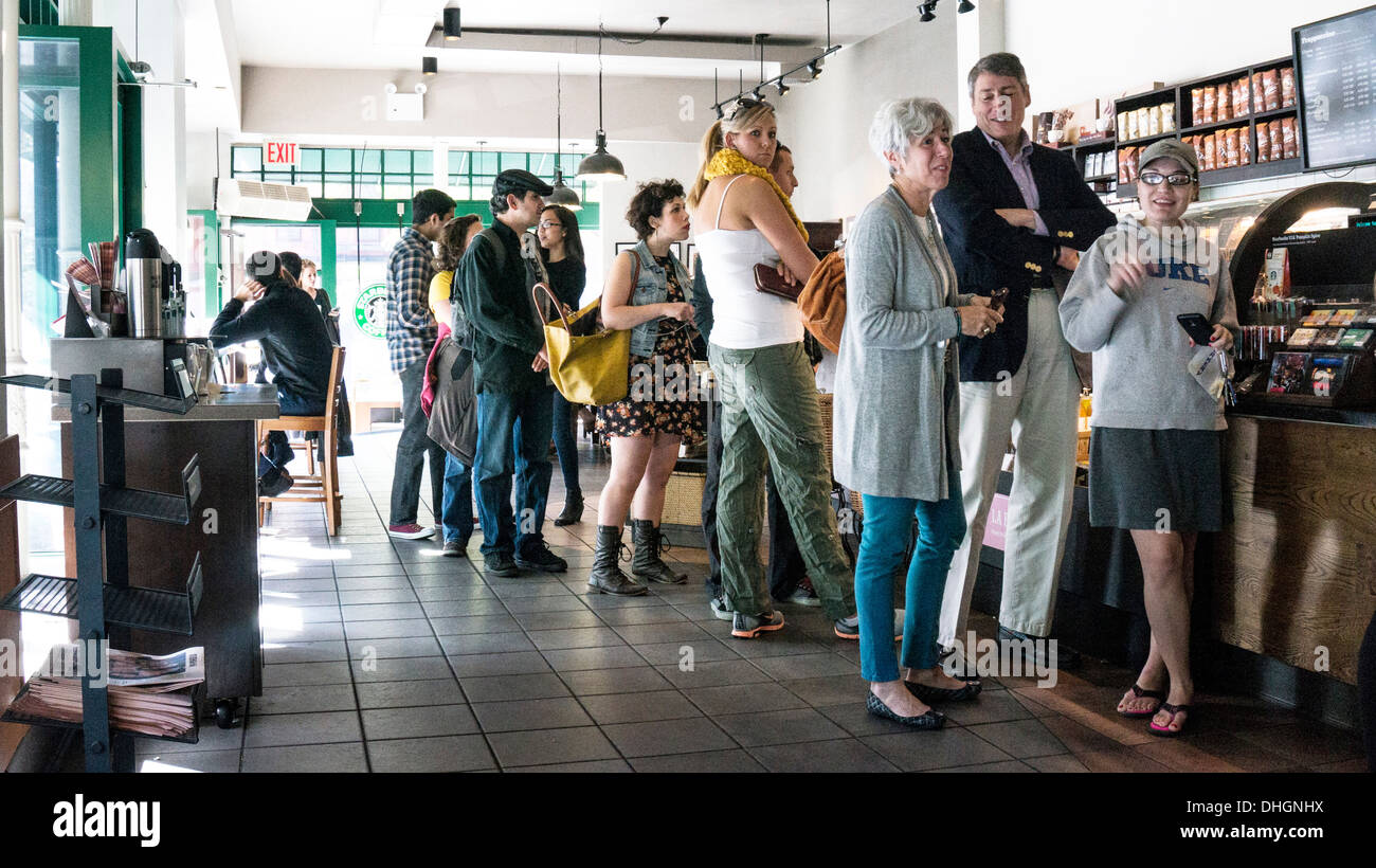 Bien soigné avec désinvolture les New-yorkais à attendre en ligne pour commander un café au Starbucks de l'upper west side de Manhattan samedi automne chaud Banque D'Images