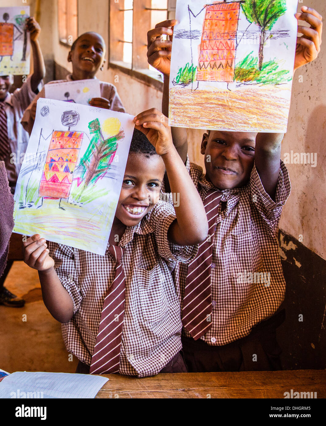 Les enfants dans une école primaire du Kenya holding fièrement leurs dessins en couleur durant une classe d'art Banque D'Images
