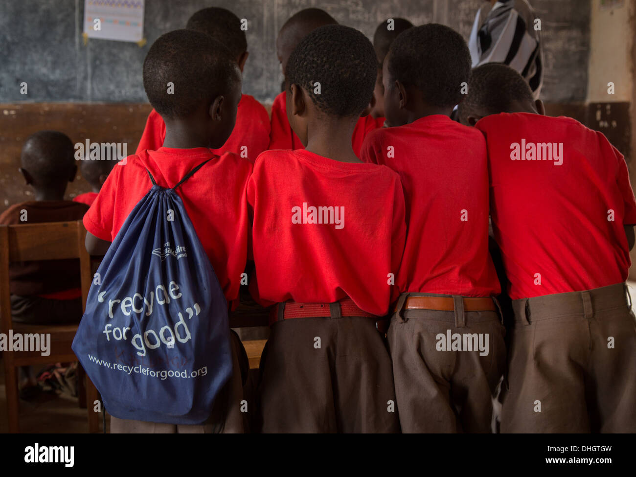 Quatre garçons de l'école d'un bureau dans une salle de classe du Kenya une avec un sac avec logo ' Recycler pour de bon ' Banque D'Images