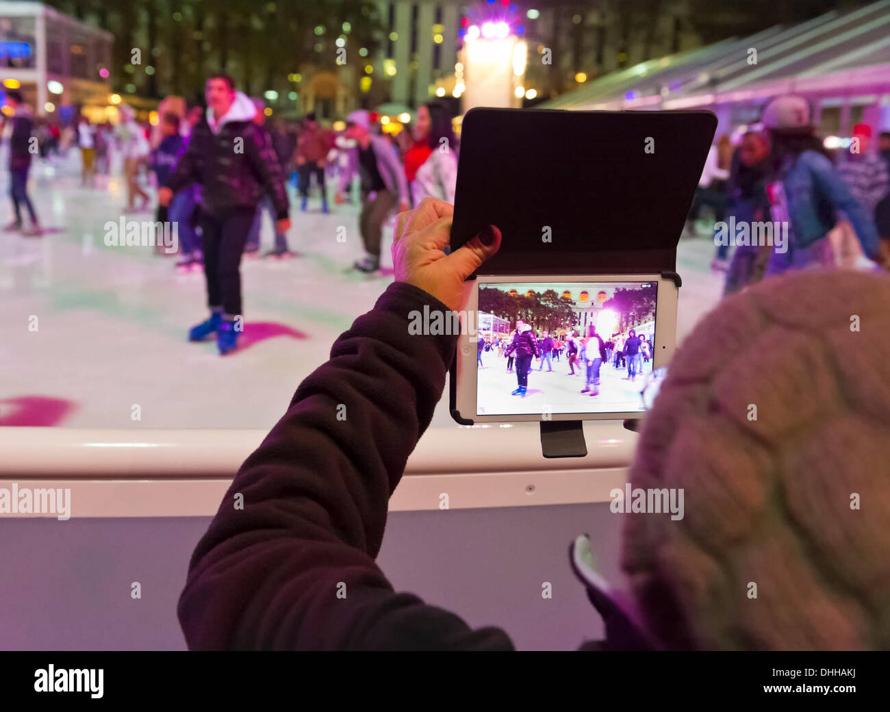 Manhattan, New York, États-Unis Le 9 novembre 2013. Les visiteurs utilisent iPad mini tablette pour prendre des photos de patineurs, au Village d'hiver patinoire à Bryant Park la nuit, © Ann E Parry/Alamy Live News Banque D'Images
