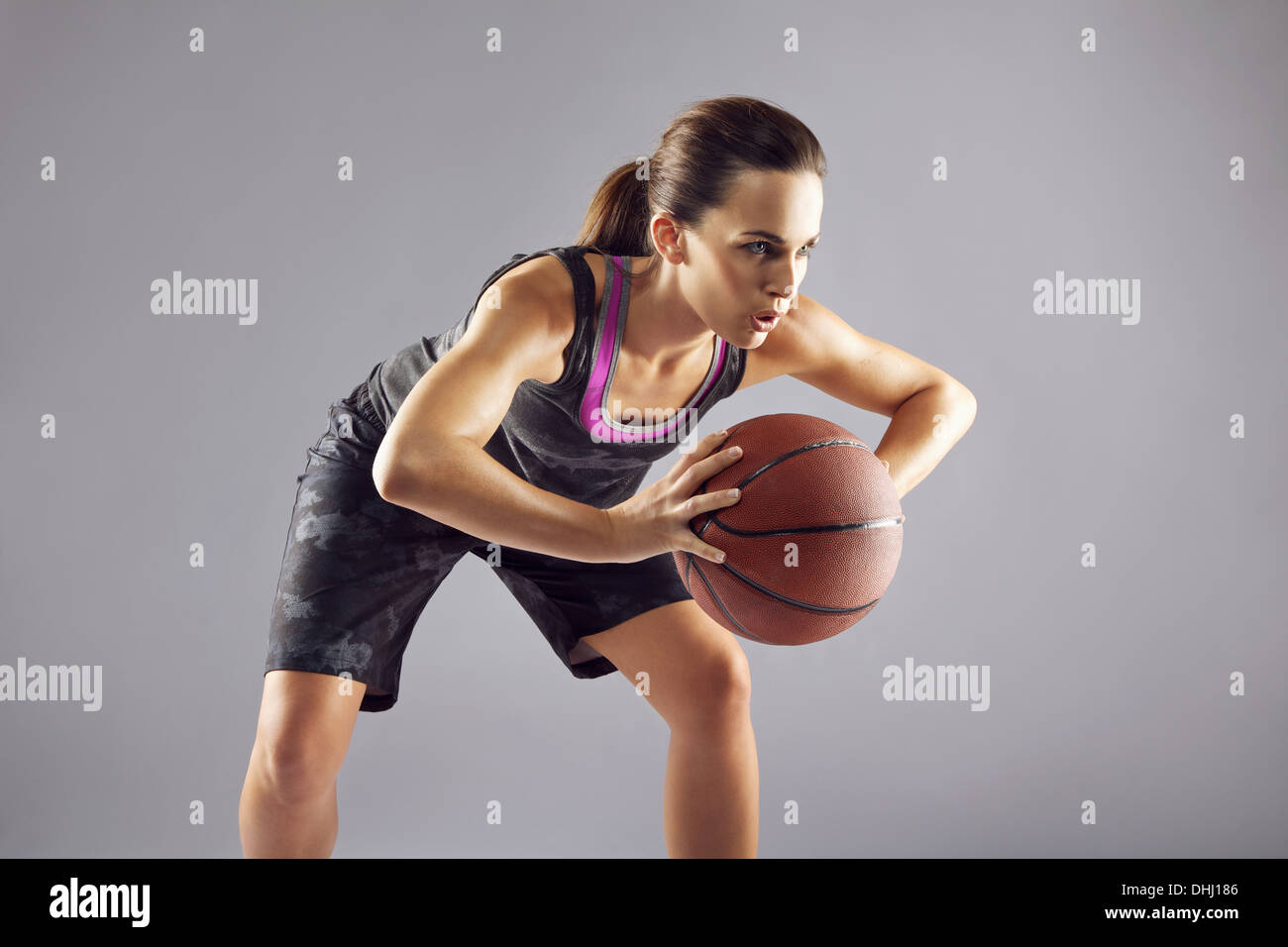 Jeune joueur de basket-ball féminin en uniforme en passant un terrain de  basket-ball. Sportswear femme en jouant au basket-ball et à l'écart sur  gris Photo Stock - Alamy