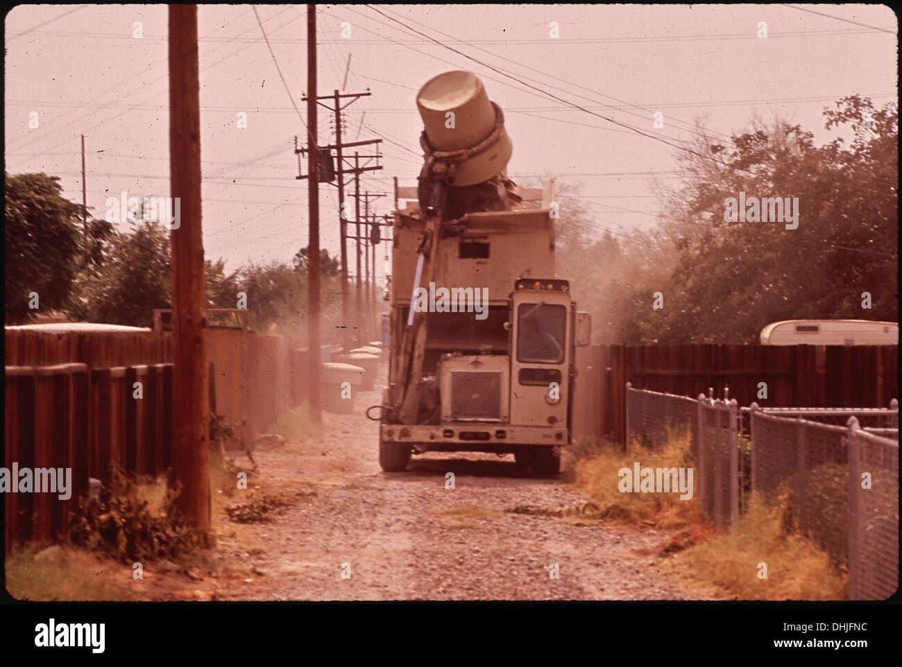 Cette image représente un bras mécanique d'un camion à ordures soulevant un conteneur à ordures de 320 gallons et déversant son contenu dans le camion. Cette innovation mécanique est devenue une caractéristique standard dans la gestion moderne des déchets. Banque D'Images