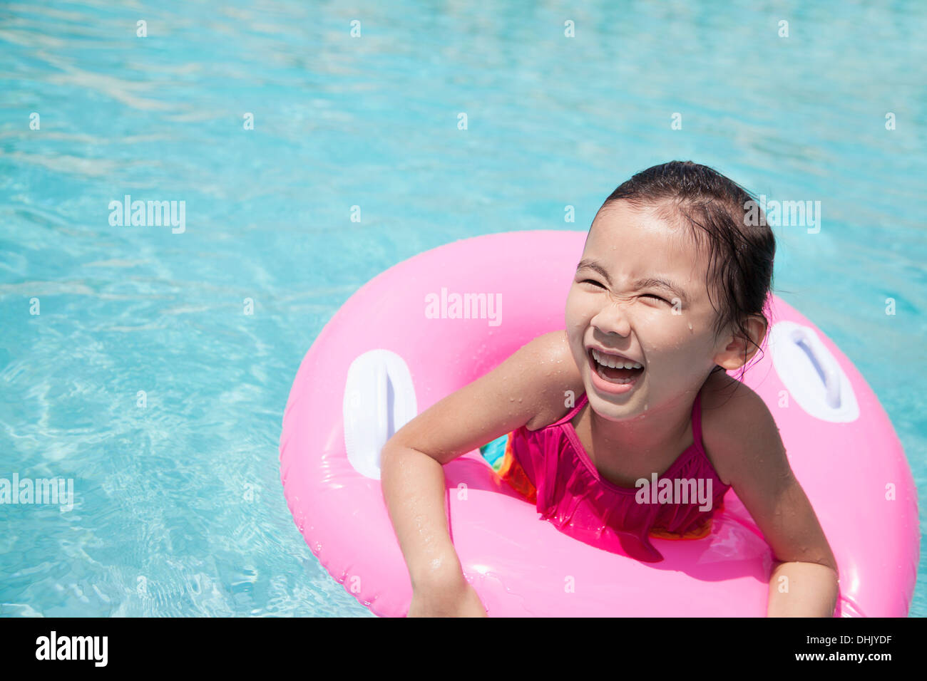 Portrait of a cute little girl la natation dans la piscine avec un tube rose Banque D'Images