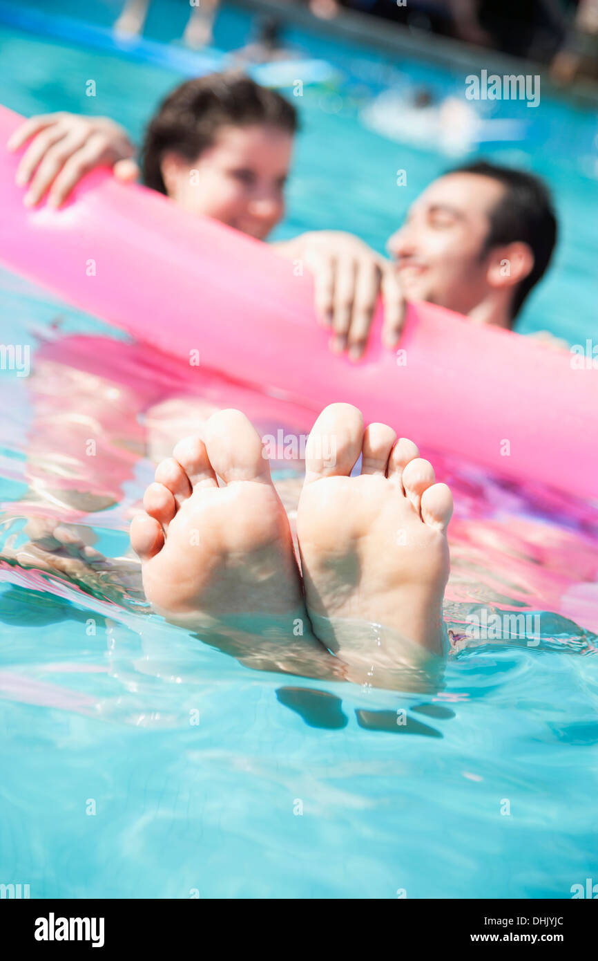 Deux amis dans une piscine la maintenant sur un radeau pneumatique avec pieds sortant de l'eau Banque D'Images