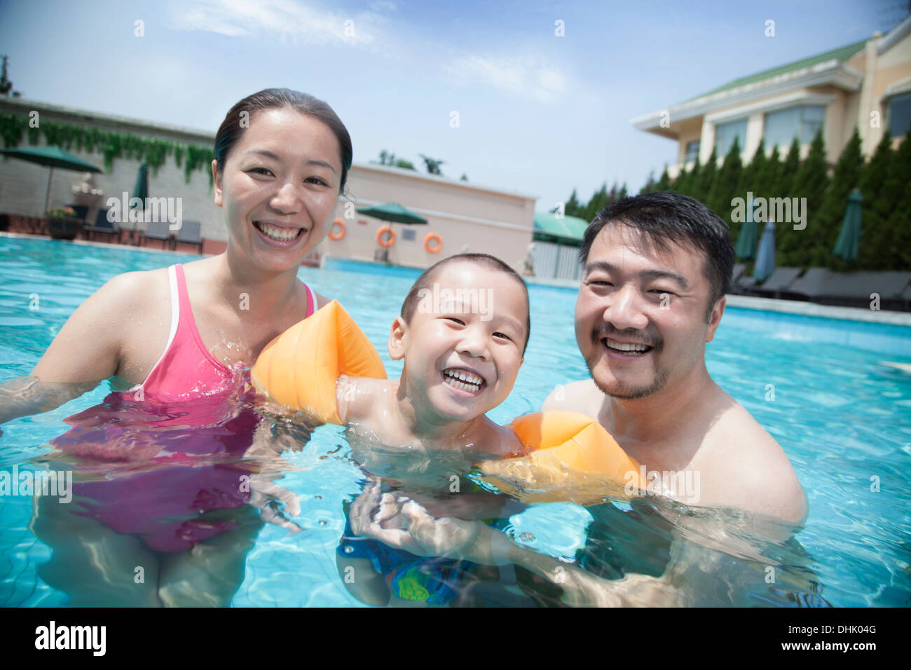 Portrait of smiling jeune famille dans la piscine en vacances Banque D'Images
