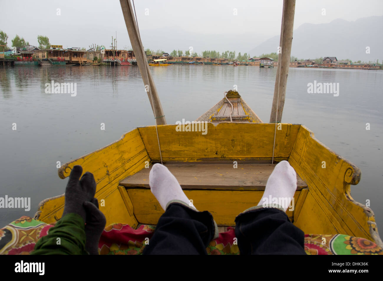 Les jambes dans une shikara et une vue de péniches dans le lac Dal à Srinagar au Cachemire en Inde. Montagnes, péniches et lac. Banque D'Images