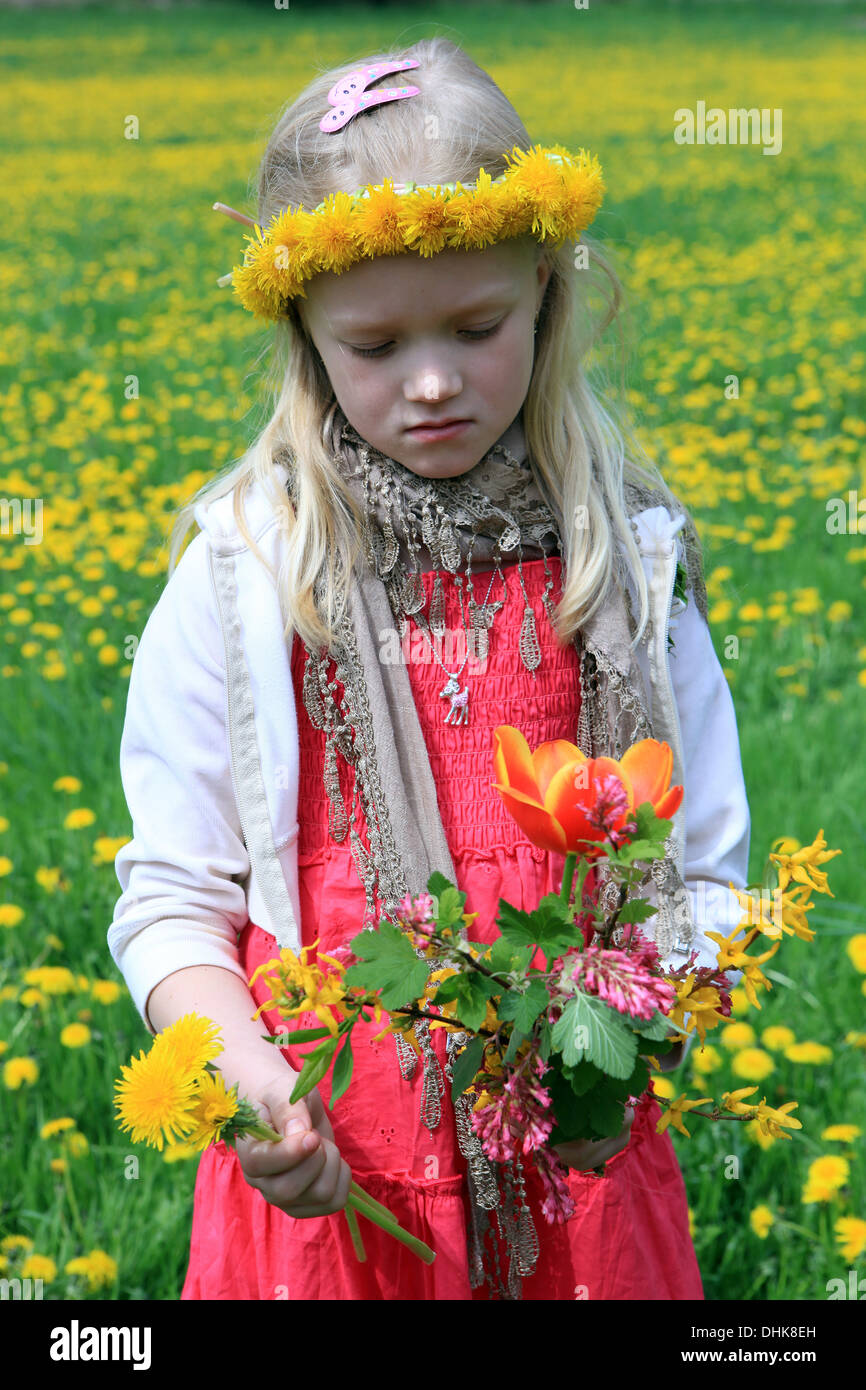 Triste jeune fille debout dans Spring Meadow avec pissenlit tête de couronne pissenlit champ fleurs de printemps mai 8-9 ans enfant seul vue de face triste fille Banque D'Images