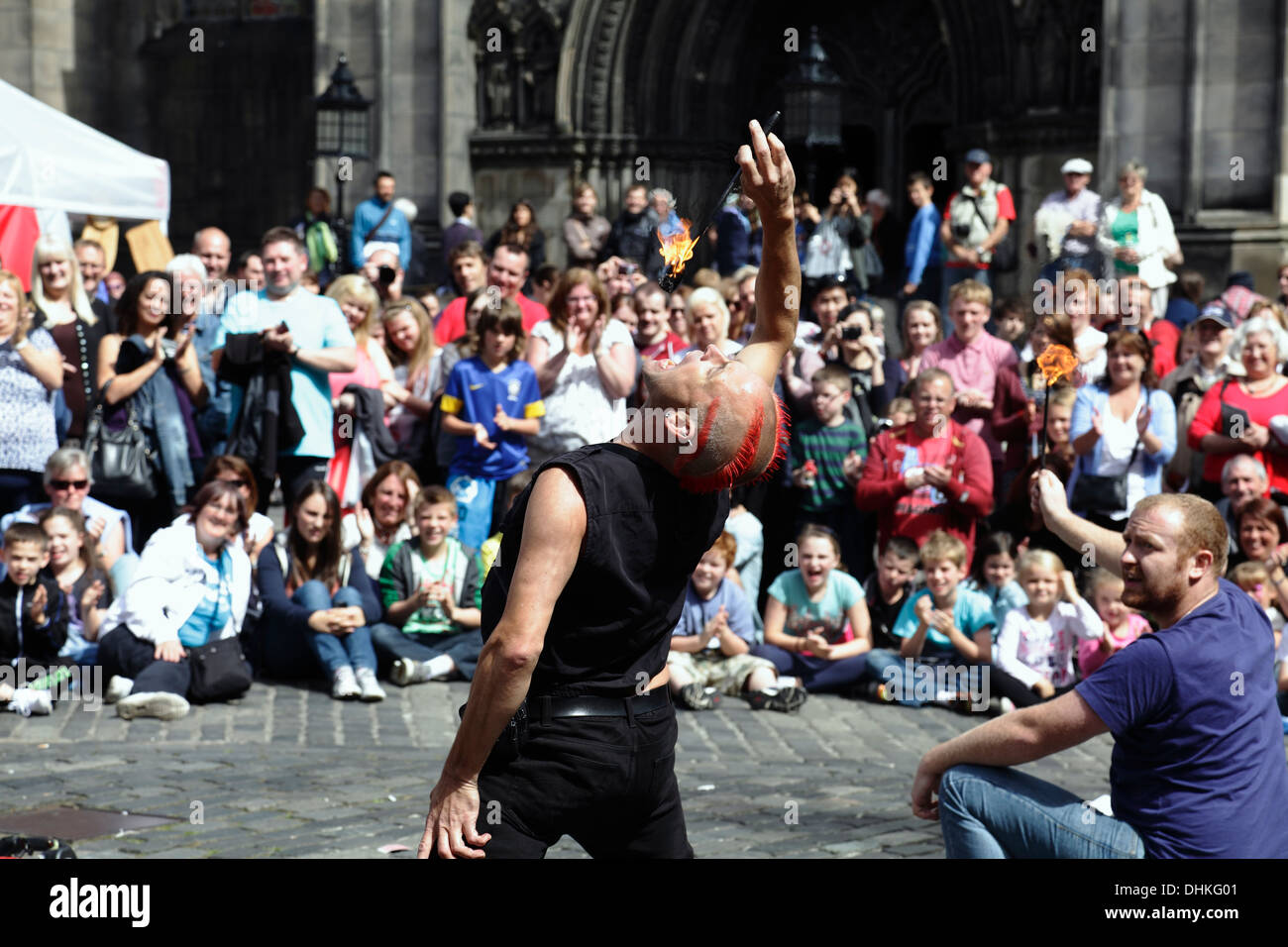 Mighty Gareth, artiste de rue, mange le feu avec l'aide d'un volontaire lors du festival international d'Édimbourg Fringe, en Écosse, au Royaume-Uni Banque D'Images