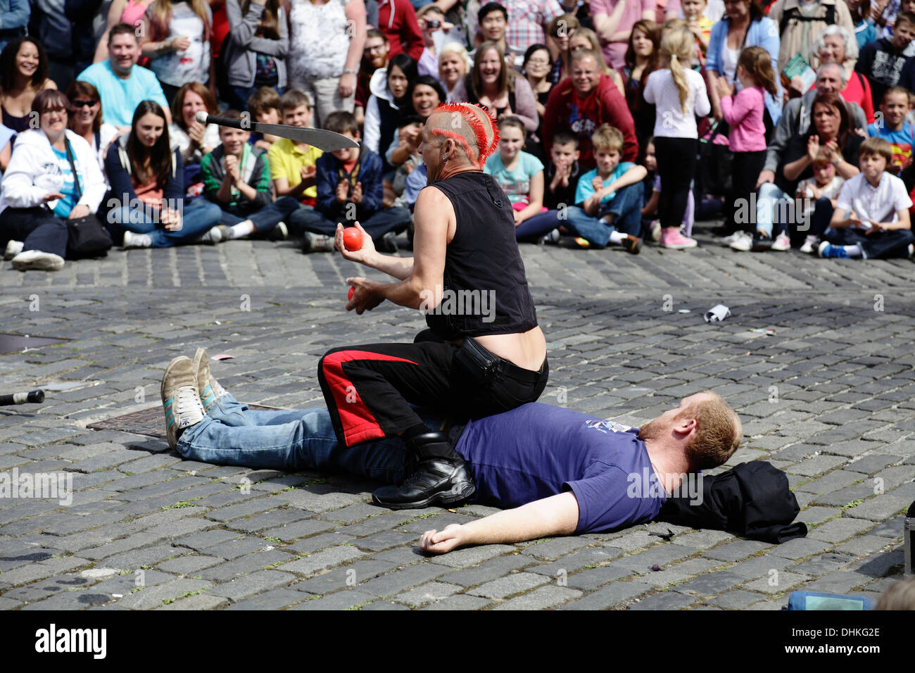 Mighty Gareth, interprète de rue, jonglant avec un couteau et des balles au-dessus d'un volontaire lors du festival international d'Édimbourg Fringe, en Écosse, au Royaume-Uni Banque D'Images