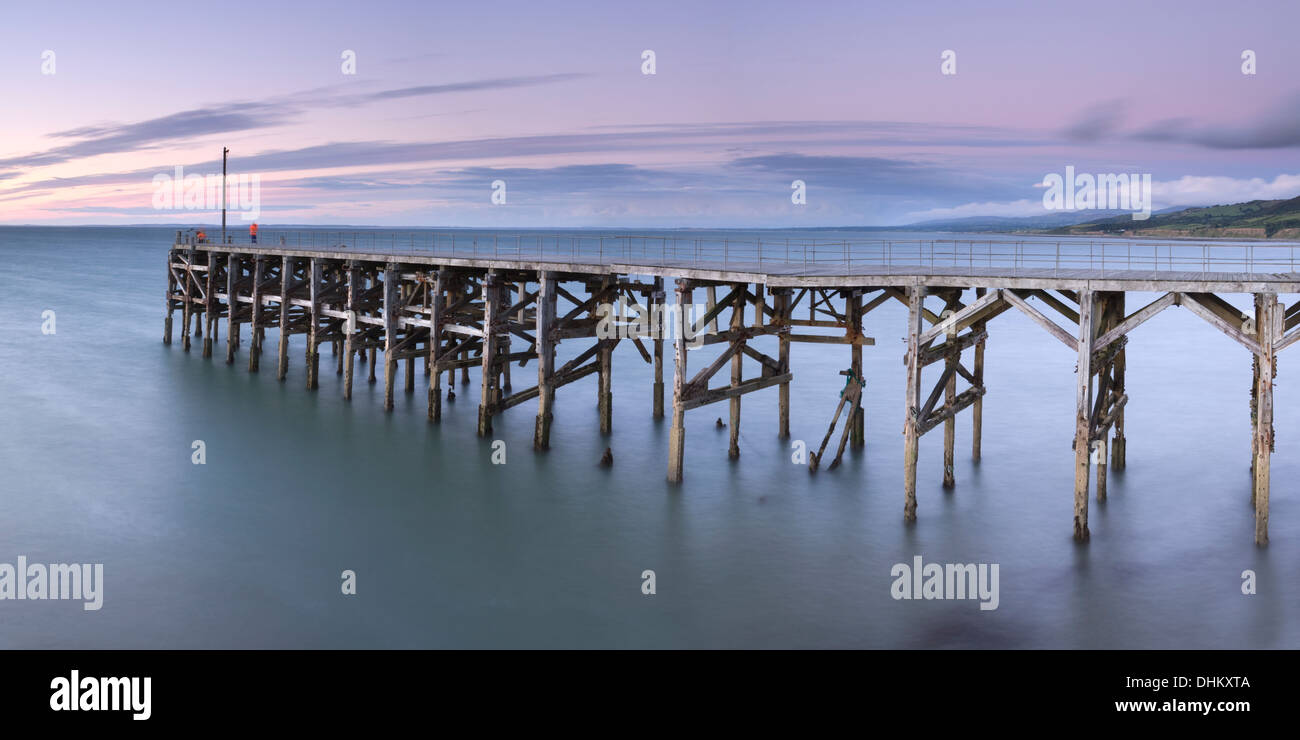 Deux pêcheurs Pêche à la suite de l'effondrement de la jetée à Trefor, Gwynedd, Pays de Galles au coucher du soleil. Banque D'Images