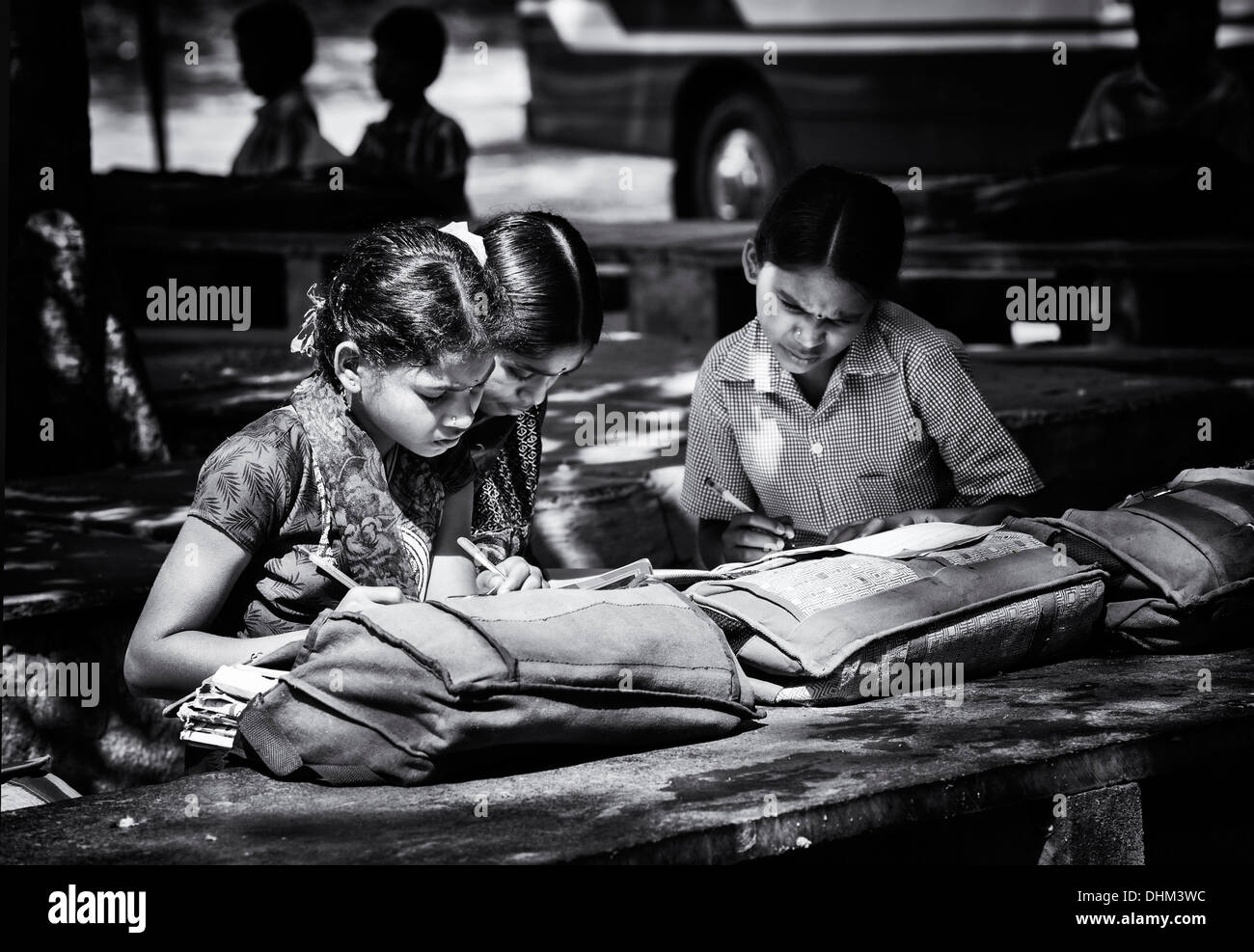 Filles de l'école de village dans l'écriture de livres écrits dans une classe de l'extérieur. L'Andhra Pradesh, Inde. Noir et blanc, selective focus. Banque D'Images