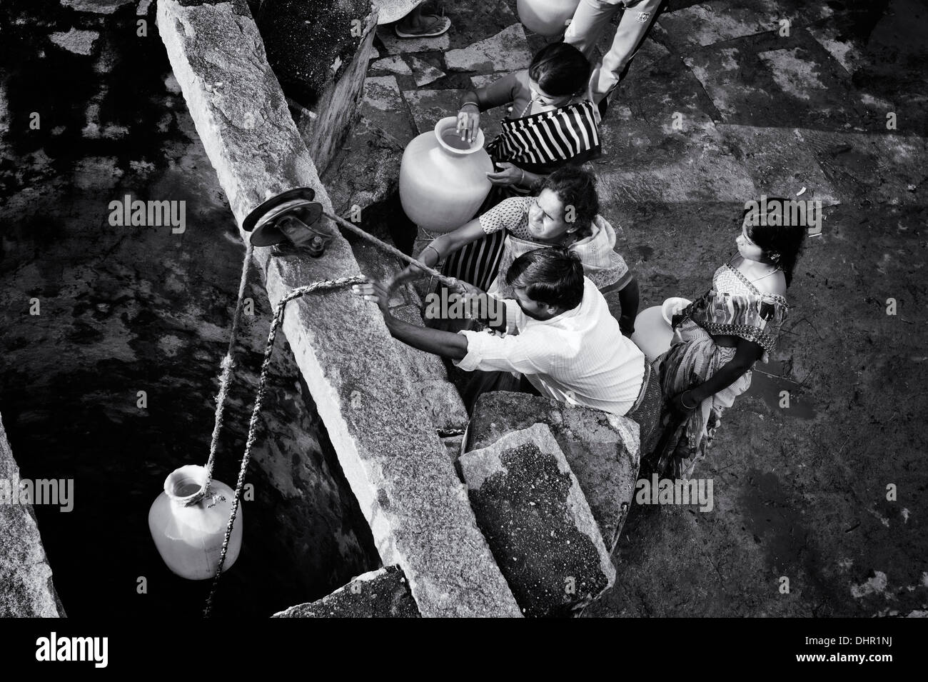 Les femmes indiennes et les hommes tirent l'eau d'un puits dans un village-rue de l'Inde rurale. L'Andhra Pradesh, en Inde . Monochrome Banque D'Images