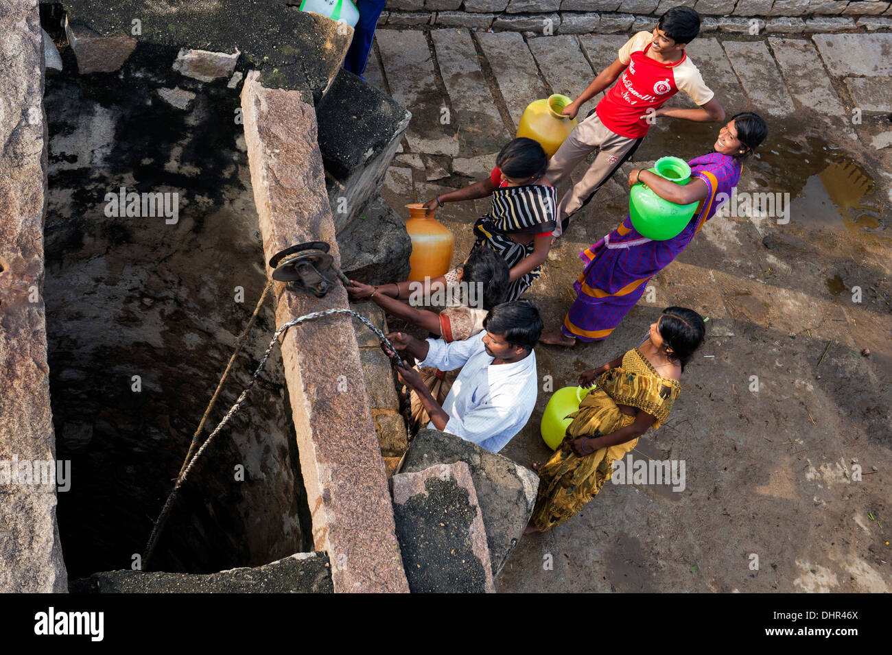 Les femmes indiennes et les hommes tirent l'eau d'un puits dans un village-rue de l'Inde rurale. L'Andhra Pradesh, Inde Banque D'Images