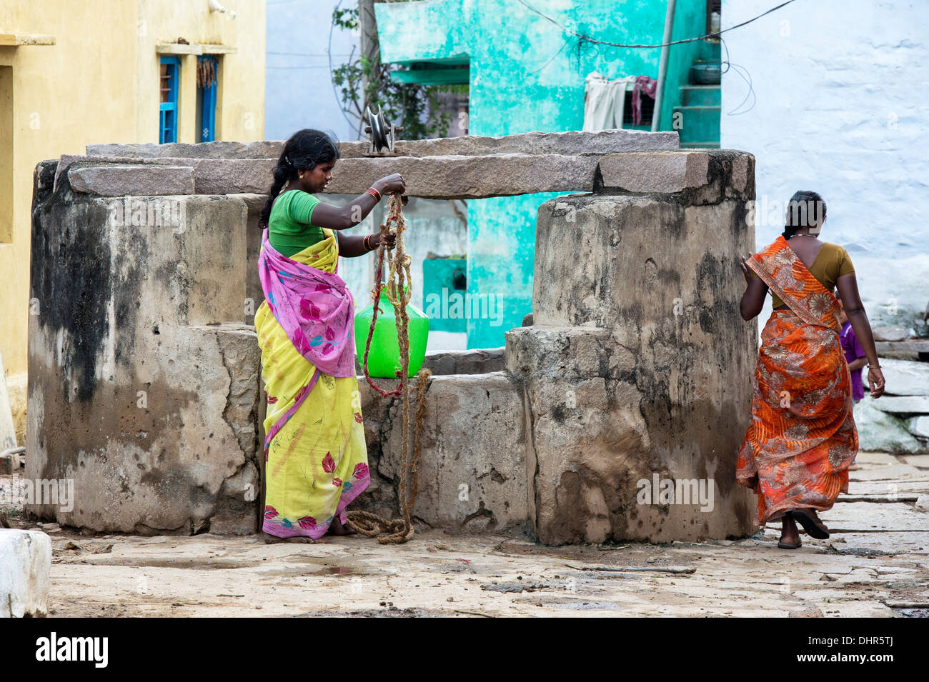Les femmes indiennes dimensions de l'eau d'un puits dans un village-rue de l'Inde rurale. L'Andhra Pradesh, Inde Banque D'Images