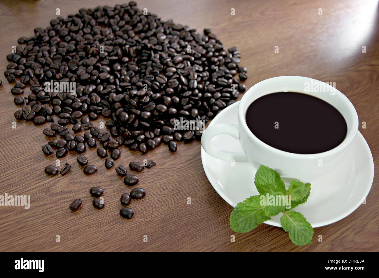 Photo des grains de café et de menthe verte près d'une tasse de café blanc. Banque D'Images