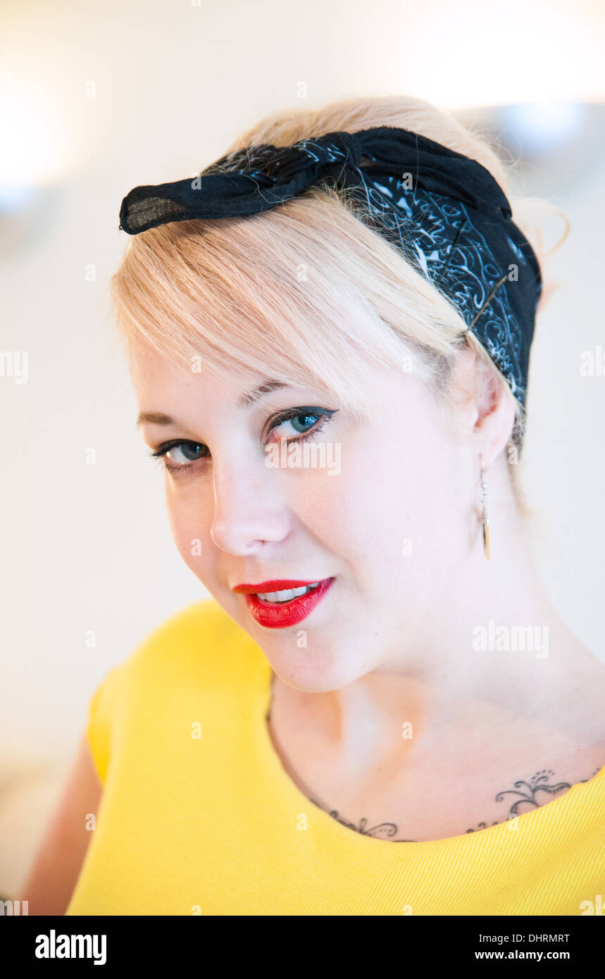 Jeune femme blonde wearing vintage 1950s style headband looking at camera smiling Banque D'Images