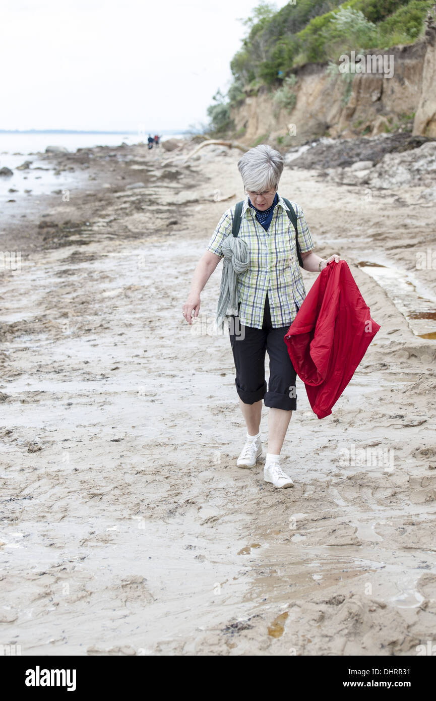 Une femme à la plage à pied sous la pluie Banque D'Images