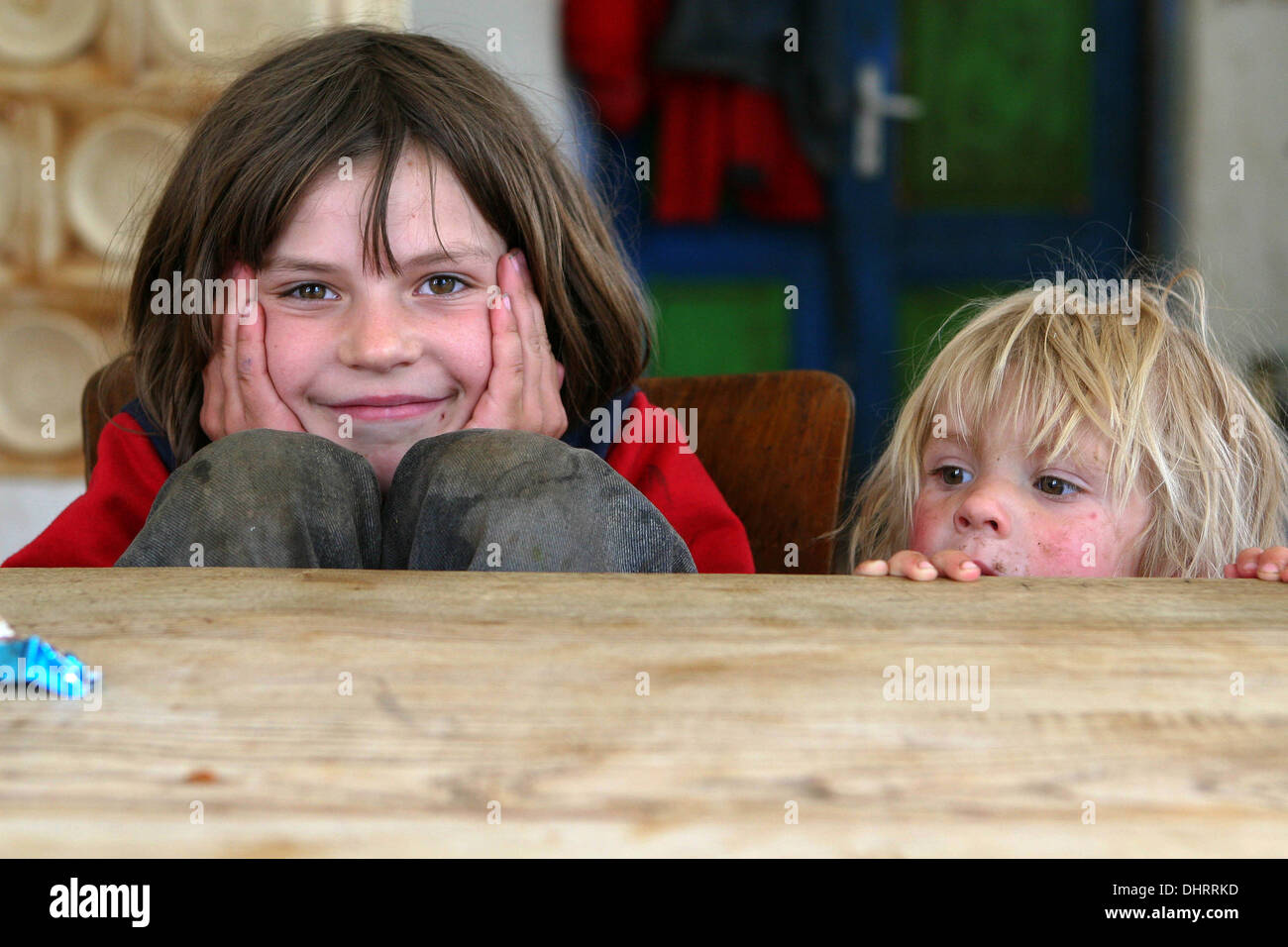 Deux enfants dans la cuisine, derrière une table à manger en bois Banque D'Images