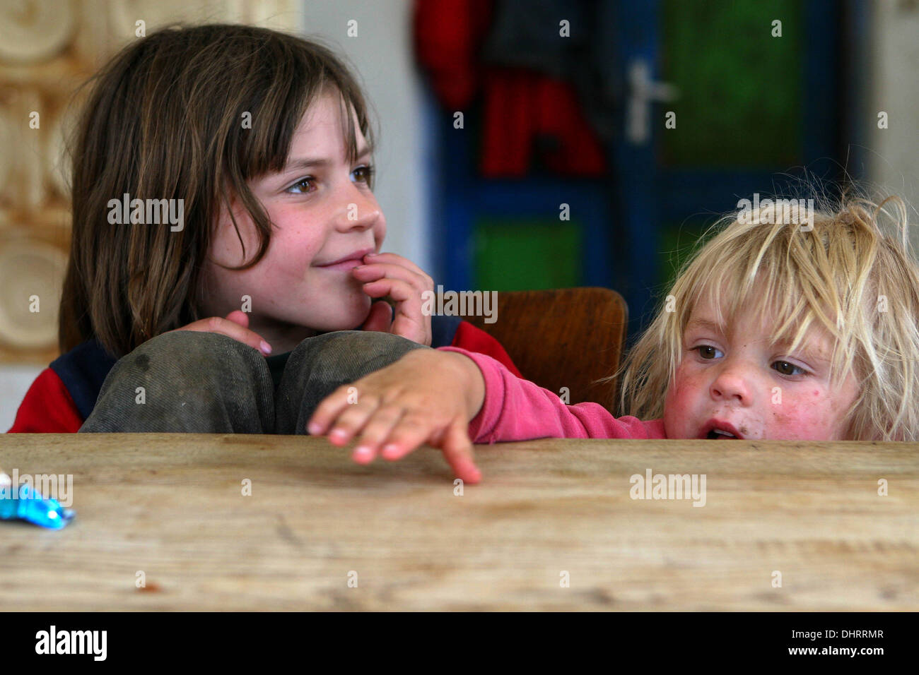 Deux enfants dans la cuisine, derrière une table à manger en bois Banque D'Images