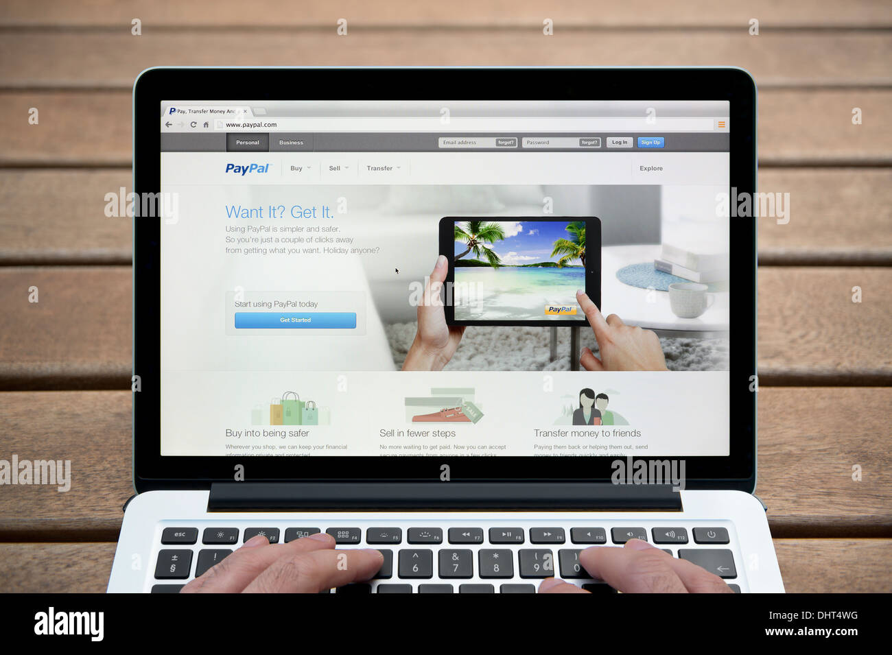 Le site Web de PayPal sur un MacBook contre un banc en bois fond de plein air y compris les doigts d'un homme (usage éditorial uniquement). Banque D'Images