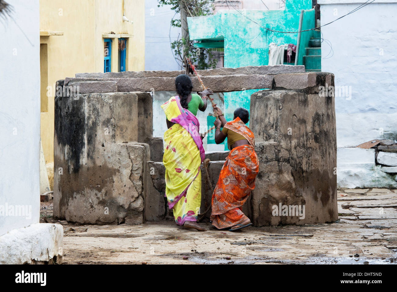 Les femmes indiennes dimensions de l'eau d'un puits dans un village-rue de l'Inde rurale. L'Andhra Pradesh, Inde Banque D'Images