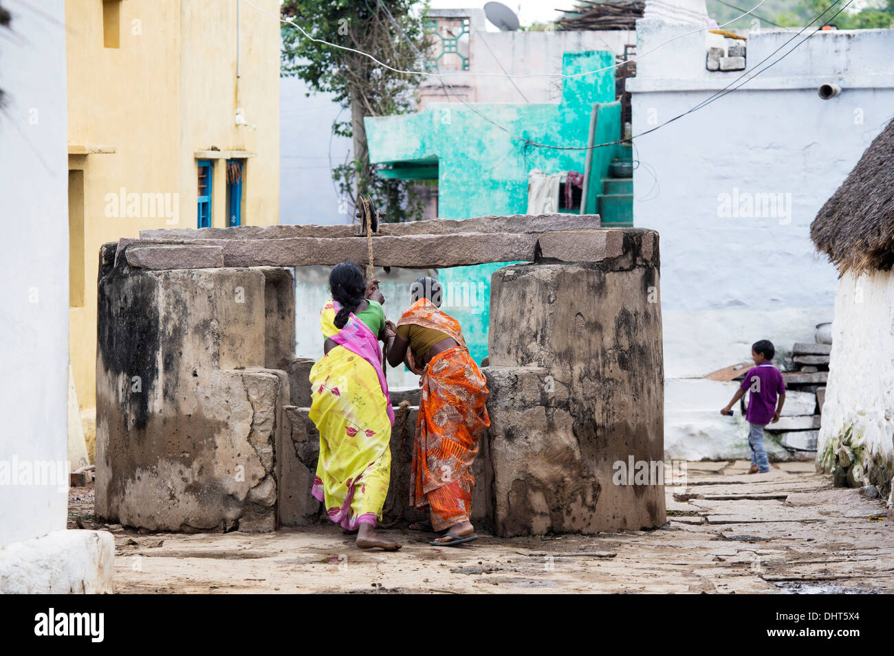 Les femmes indiennes dimensions de l'eau d'un puits dans un village-rue de l'Inde rurale. L'Andhra Pradesh, Inde Banque D'Images