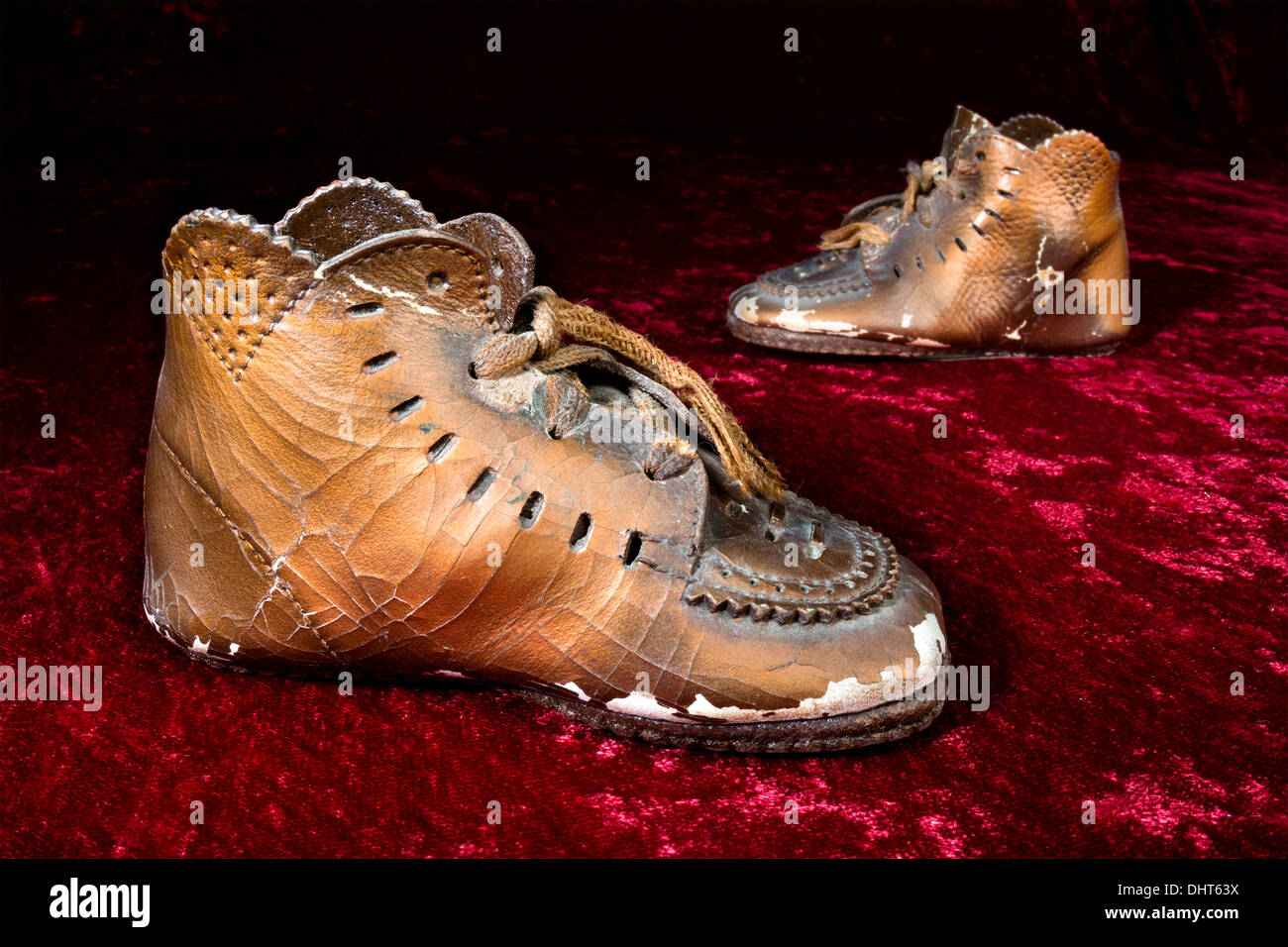 Une vieille paire de chaussures de bébé bronzé, meubles anciens sur velours rouge classique. Banque D'Images